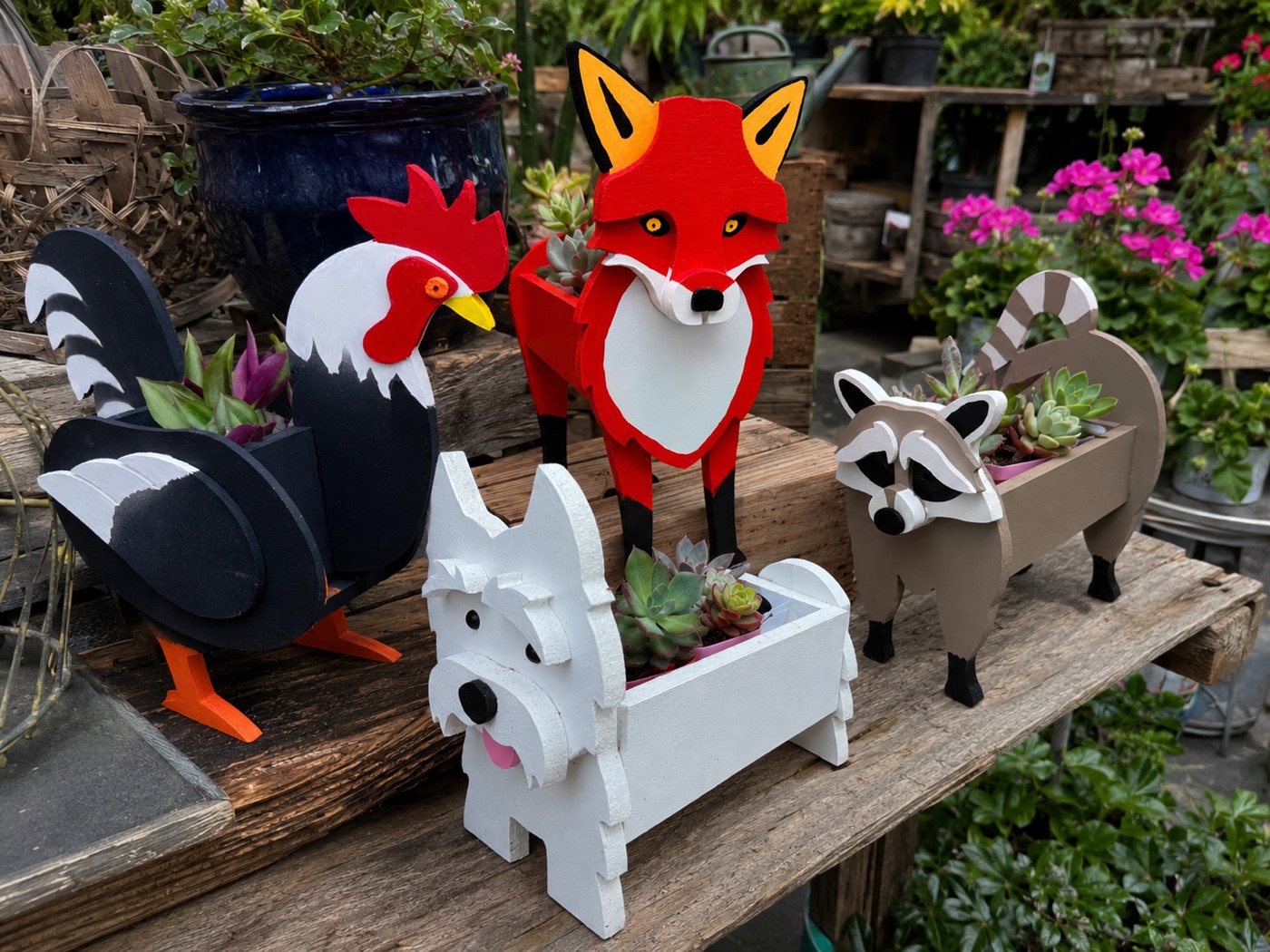 Group of rooster, fox, dog, and raccoon planters arranged on a wooden table